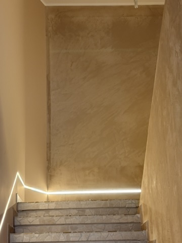 Vano scala con parete uniformata e illuminazione lineare